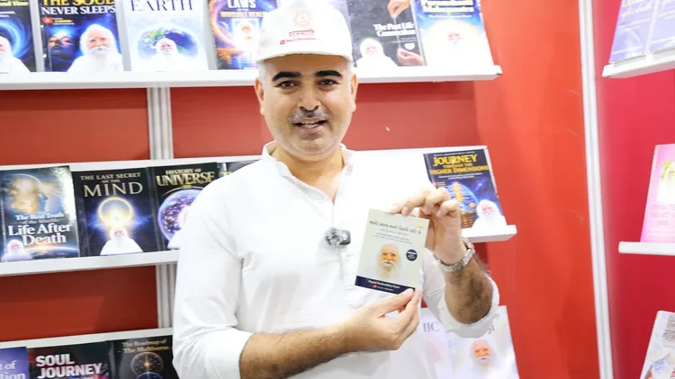 A volunteer smiles while holding up a pocket book at the stall