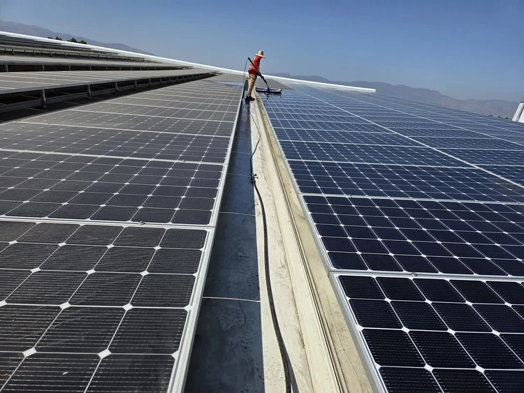 Panel-cleaning work along the rows of a commercial rooftop array