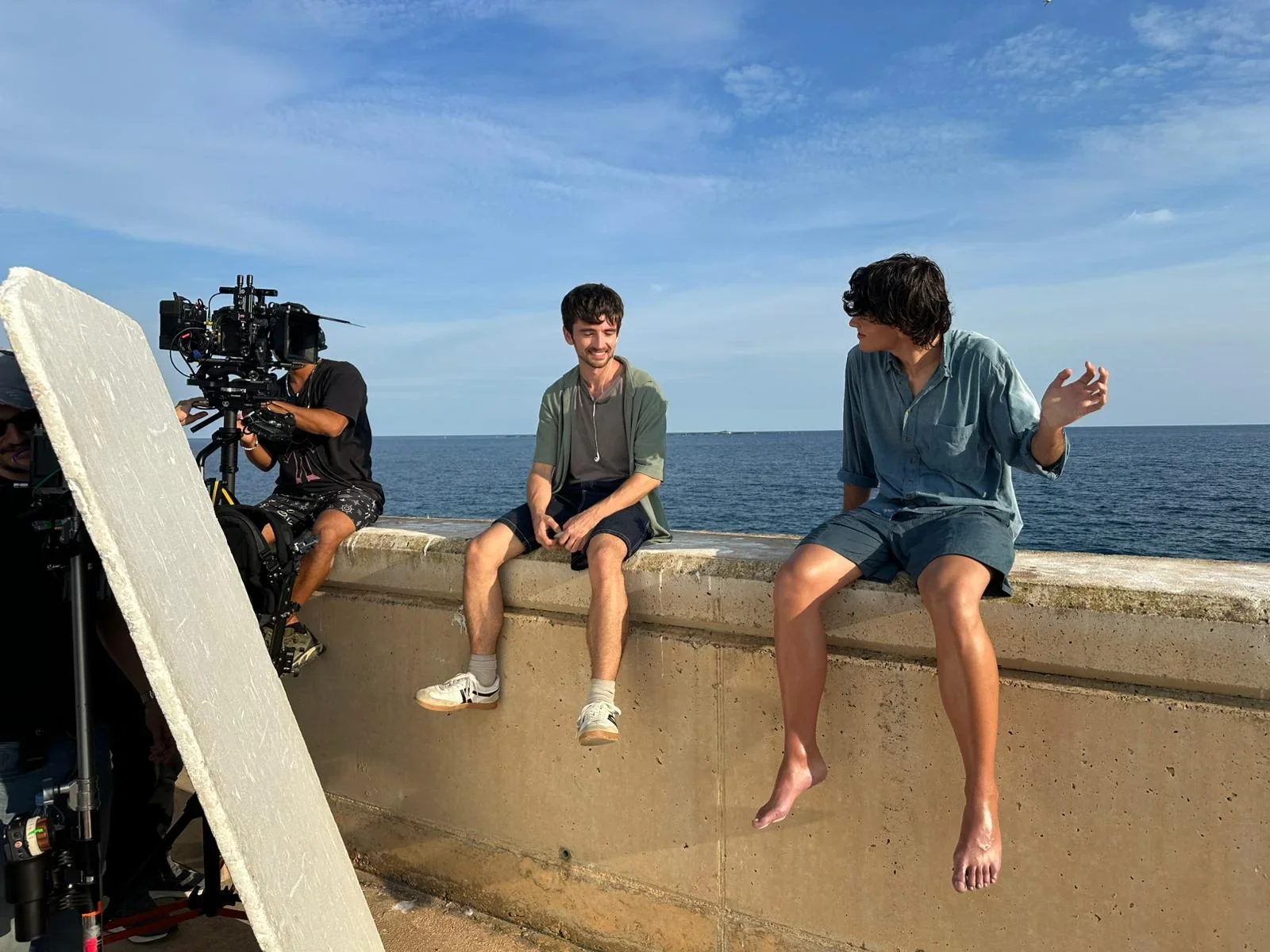 El equipo filma a los protagonistas sentados frente al mar.