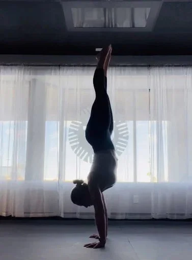A student in a handstand against the studio's window wall at Central Florida Power Yoga