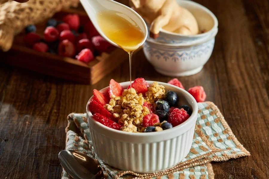Honey poured over a bowl of granola and fresh berries