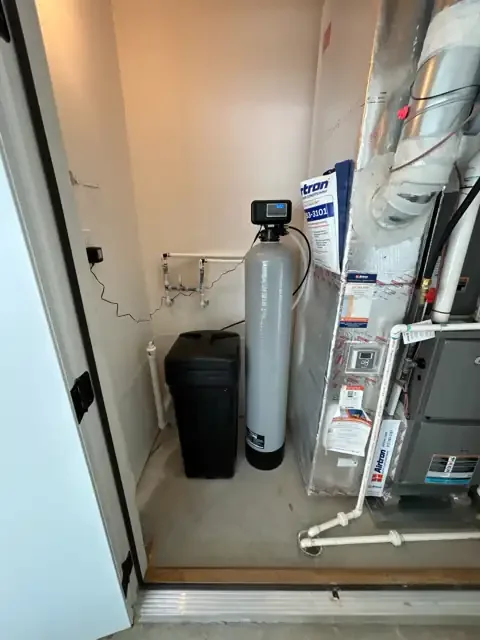 1.5 cubic foot Watco water softener with gray mineral tank, digital control head and black brine tank installed in a Carmel mechanical closet