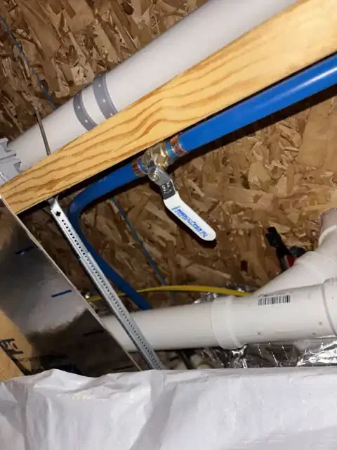 Blue PEX water line with a NIBCO PEX ball valve shutoff inside the home