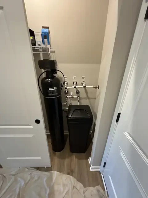 Customer-provided AquaSure water softener and brine tank installed in a McCordsville closet with labeled House, Hose Bibs and Water Main valves