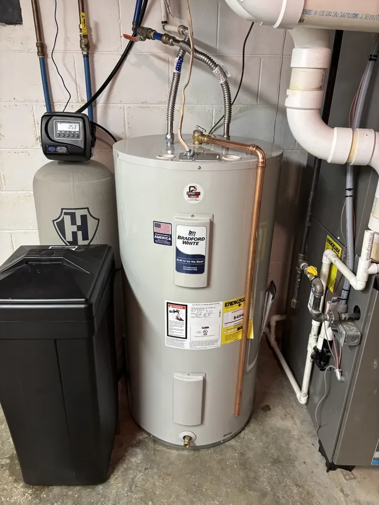 New Bradford White electric water heater with stainless flex connectors and copper relief line in a Carmel basement