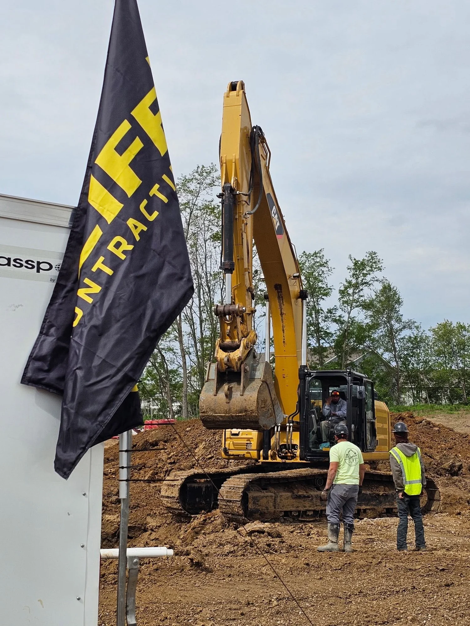 Cliff Contracting flag beside an excavator and crew at a job site