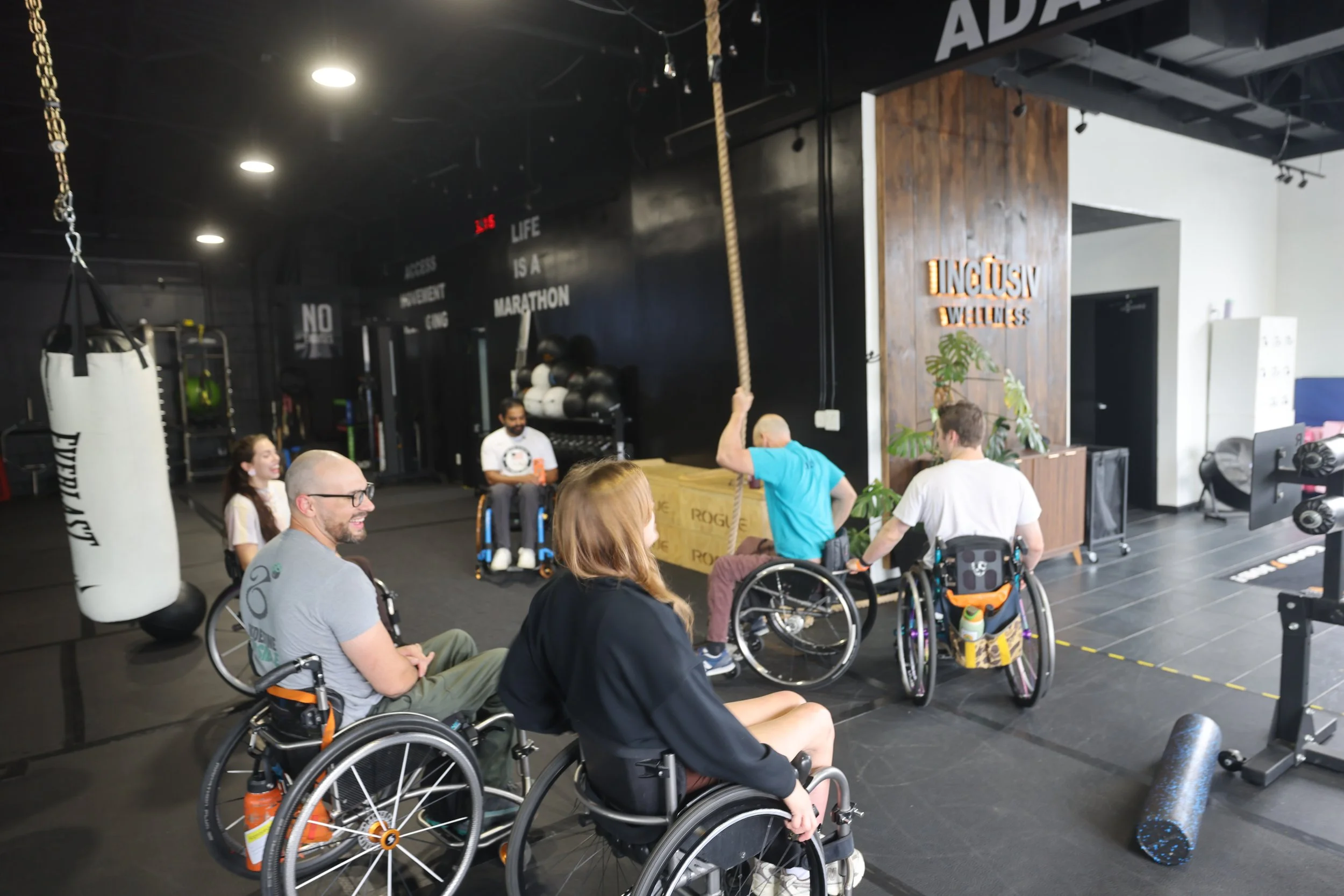 Members in wheelchairs gathered for a group session at INCLŪSIV Wellness