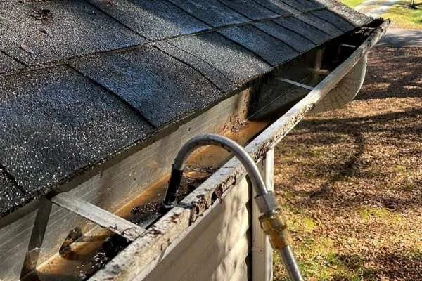 Technician cleaning gutters with ladder stabilizers