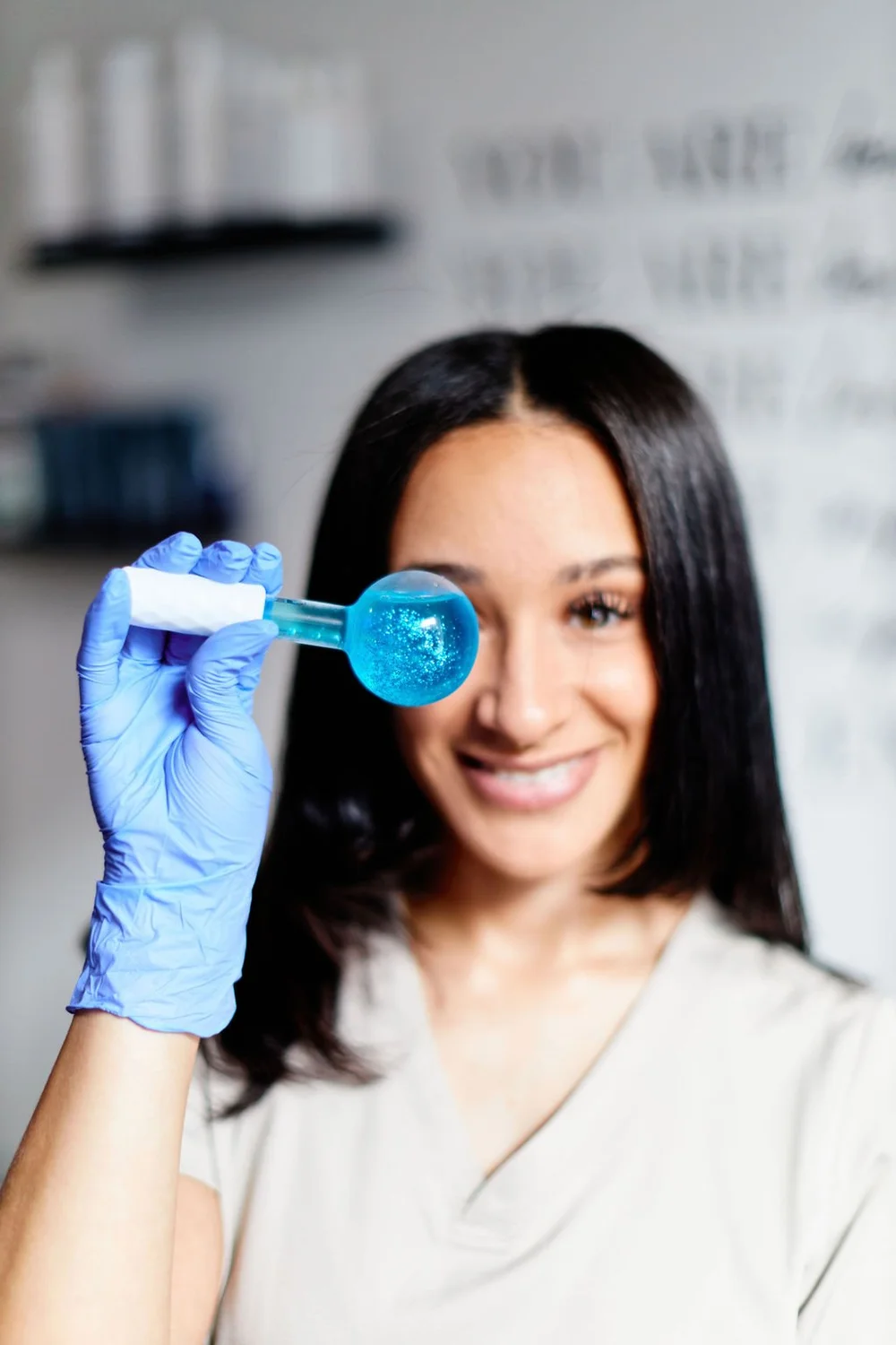 Hazel smiling while holding a cryo facial globe in her Philadelphia skincare studio