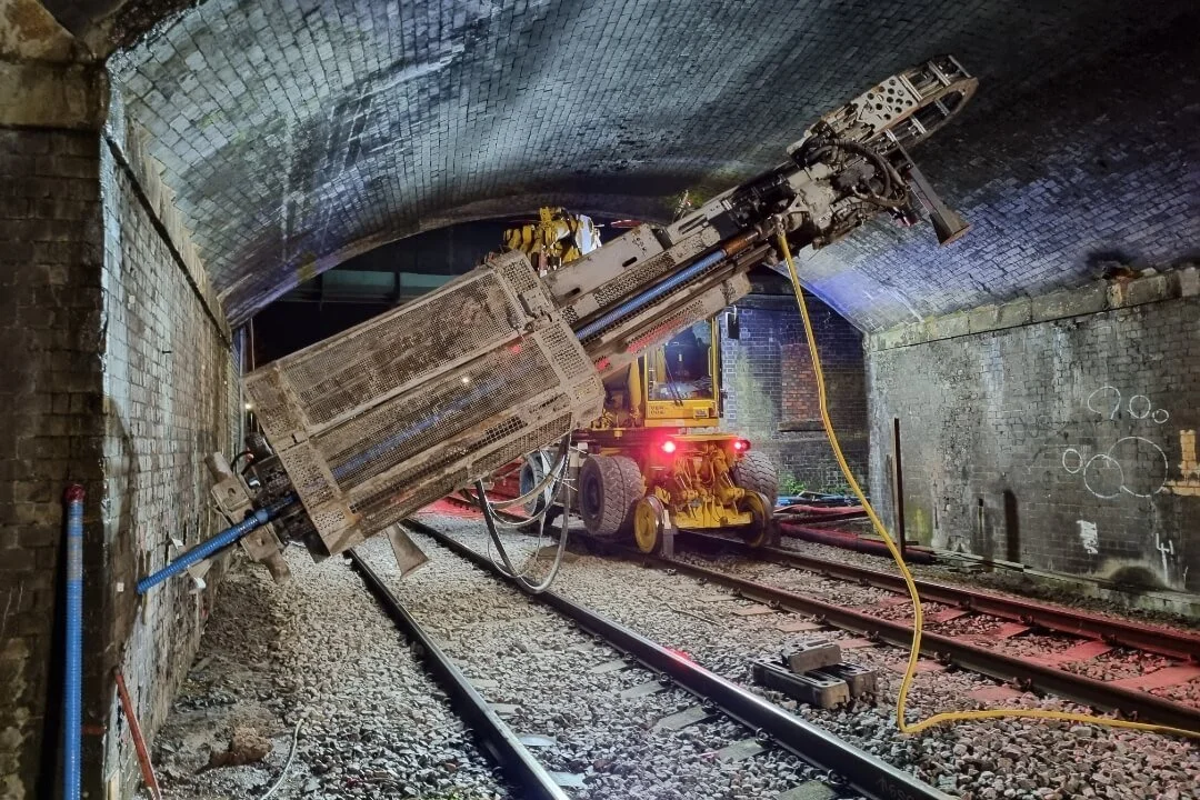 A specialised rail-mounted drilling rig performing geotechnical assessments into the brick wall of a railway tunnel in the North East.