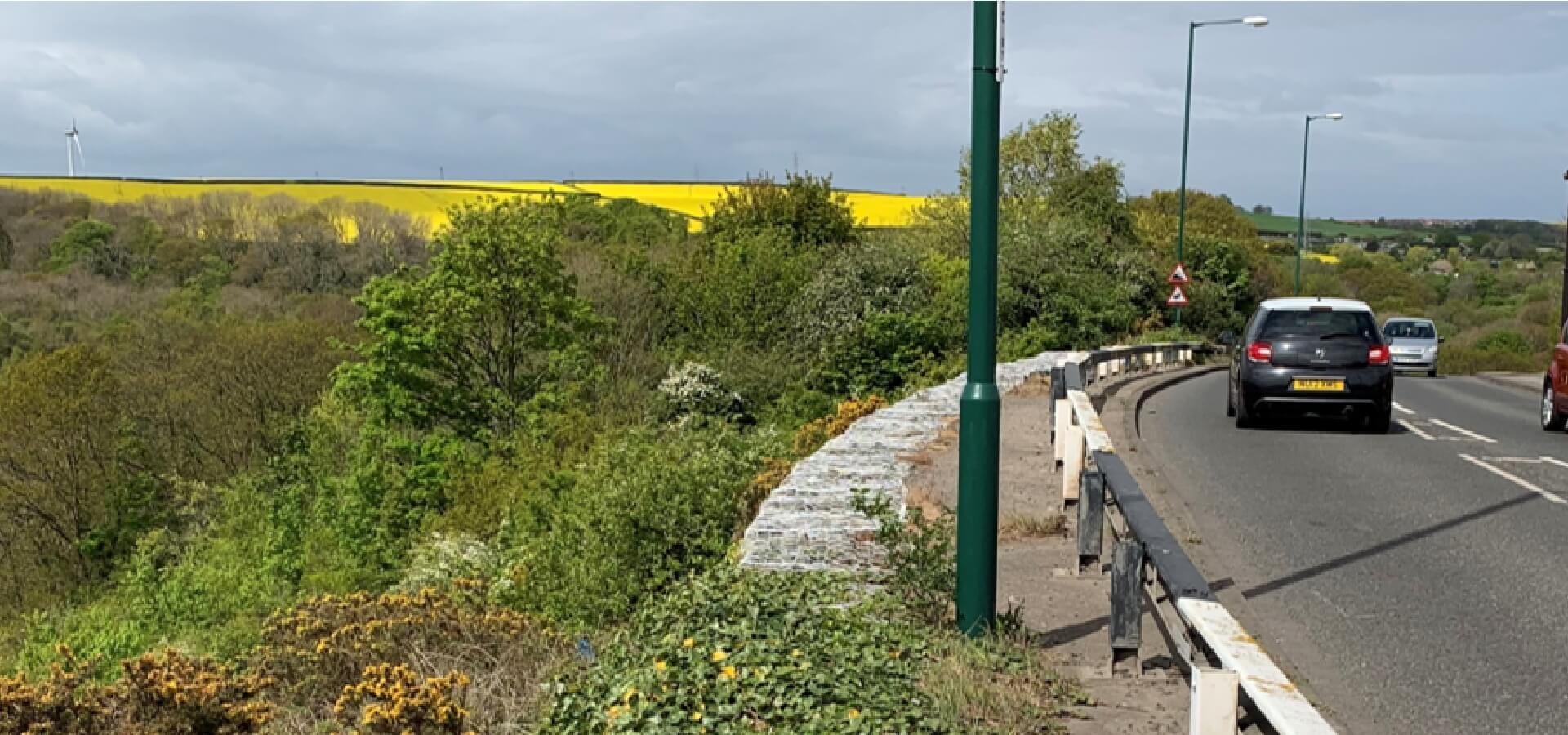 A174 at Loftus Bank beside the steep wooded valley-side slope