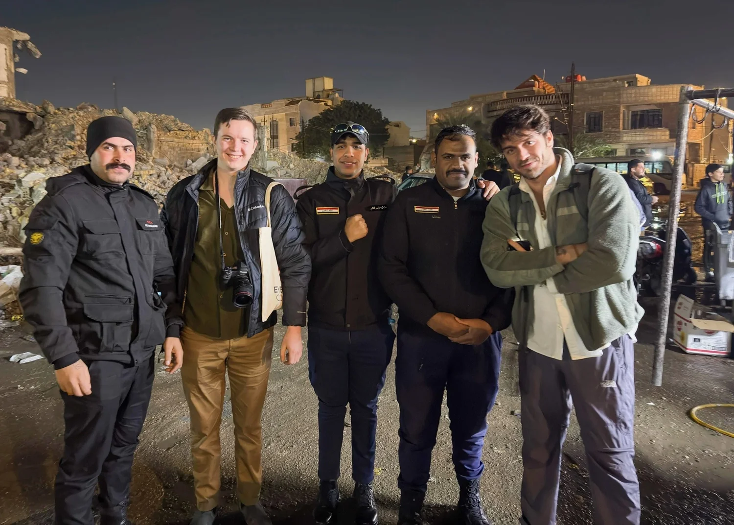 Workshop participants pose with a group in an outdoor market at night.