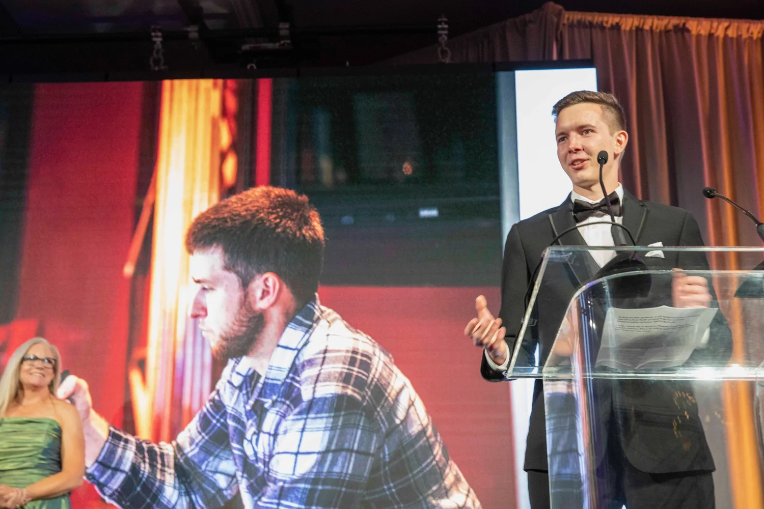 A speaker addresses an audience at a formal photography event.