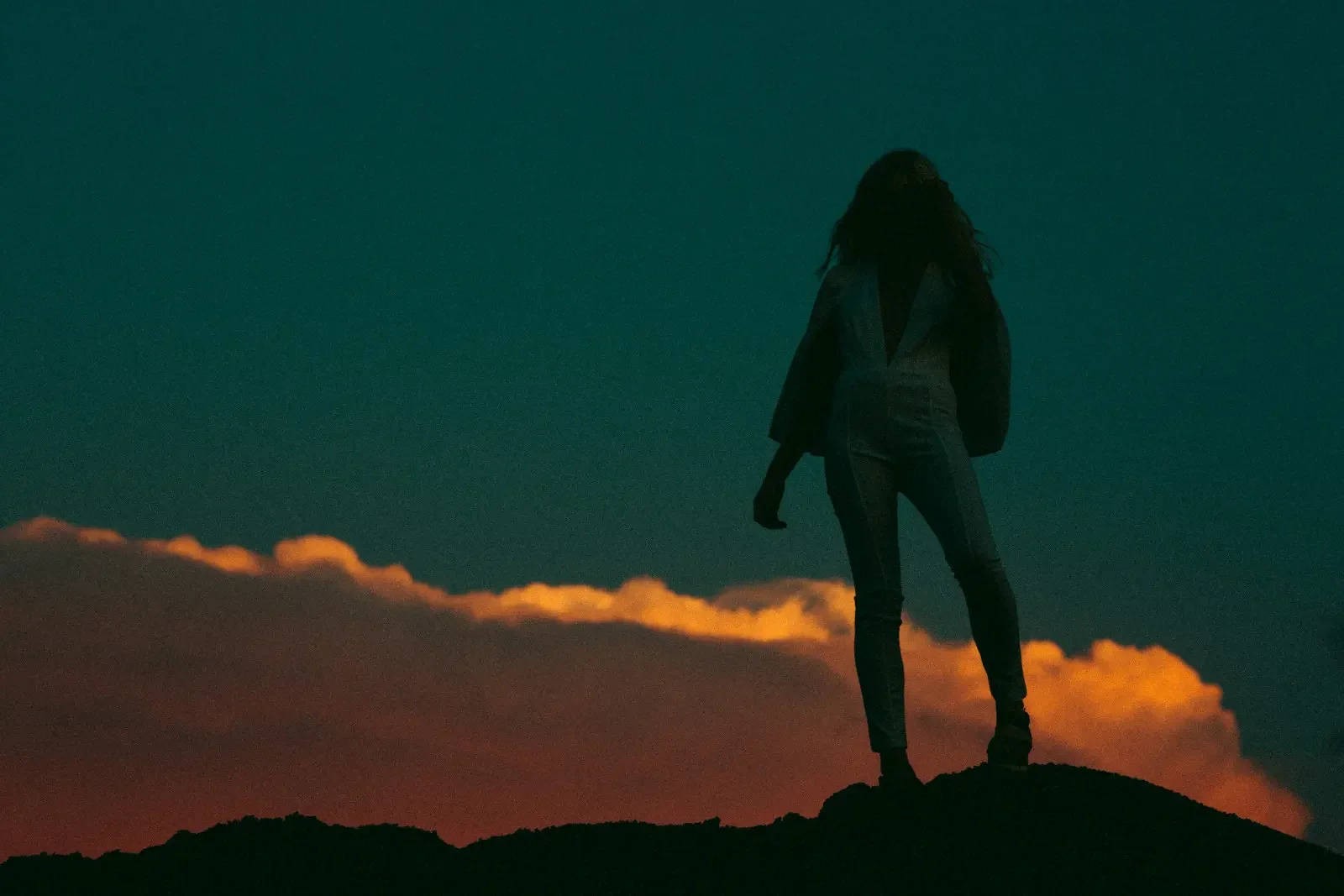 A woman at the top of a mountain at dawn. Values based actions took her to the top.