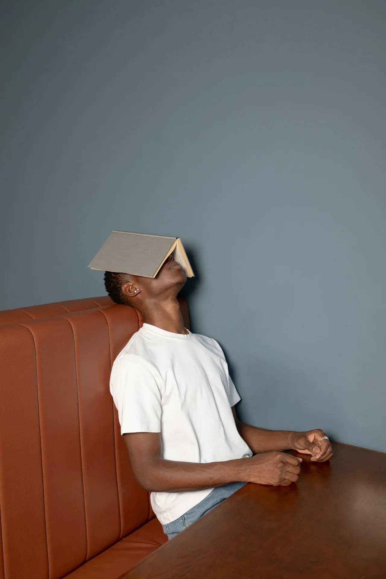 Person slumped face-down onto an open book, worn out while researching how to get an ADHD diagnosis