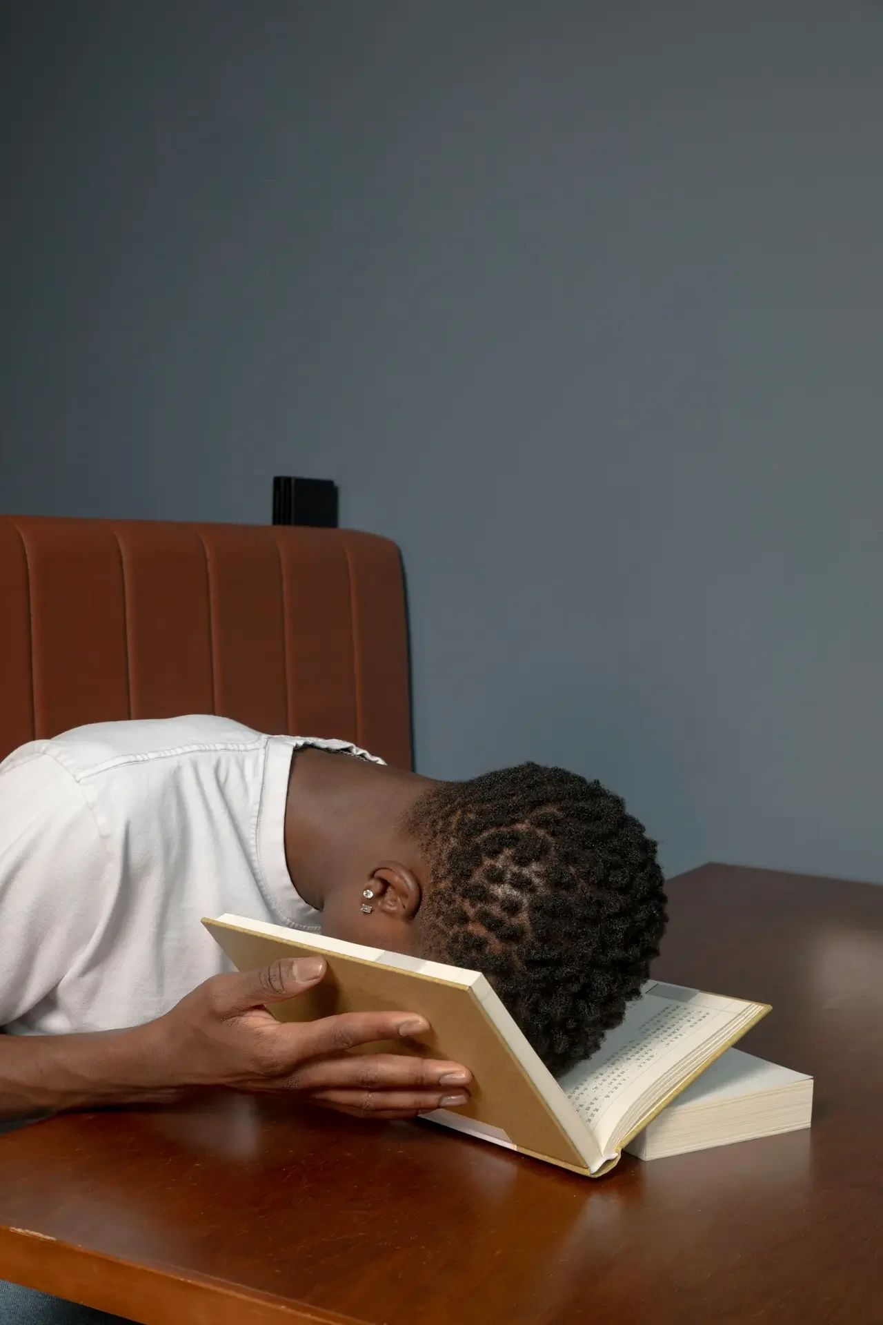 Person leaning back with an open book resting over their face, overwhelmed by conflicting information about getting an ADHD diagnosis