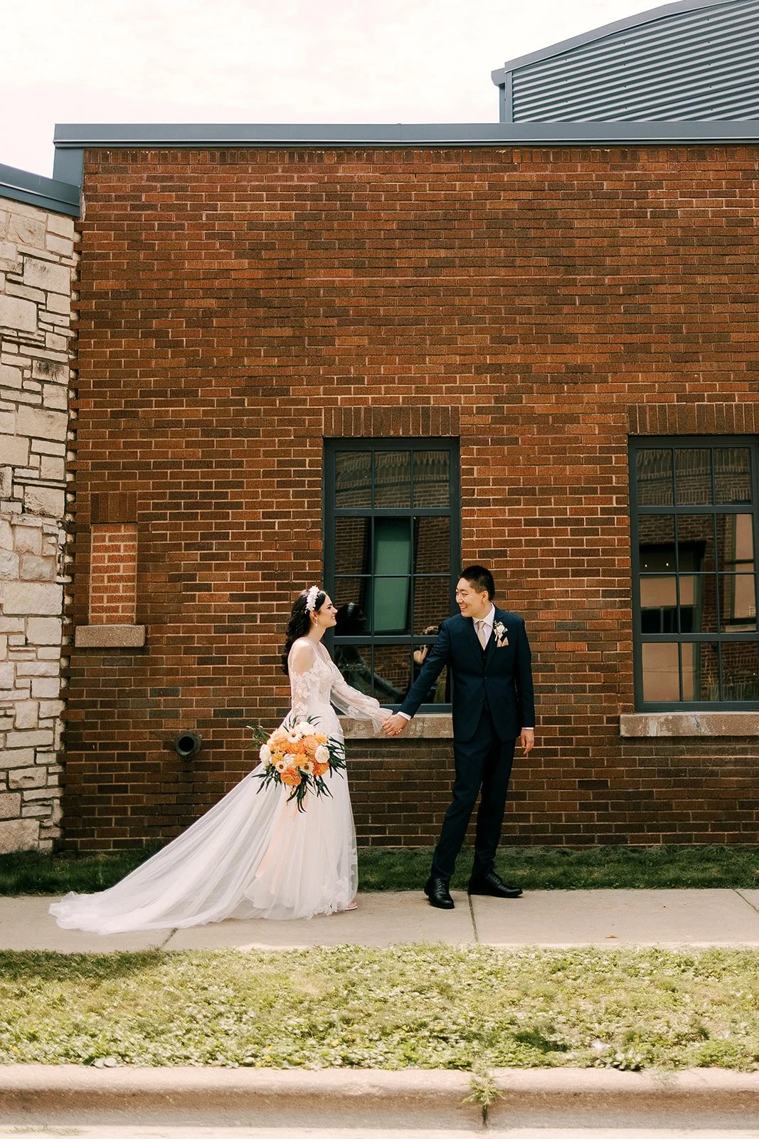 A couple holding hands outside a brick building
