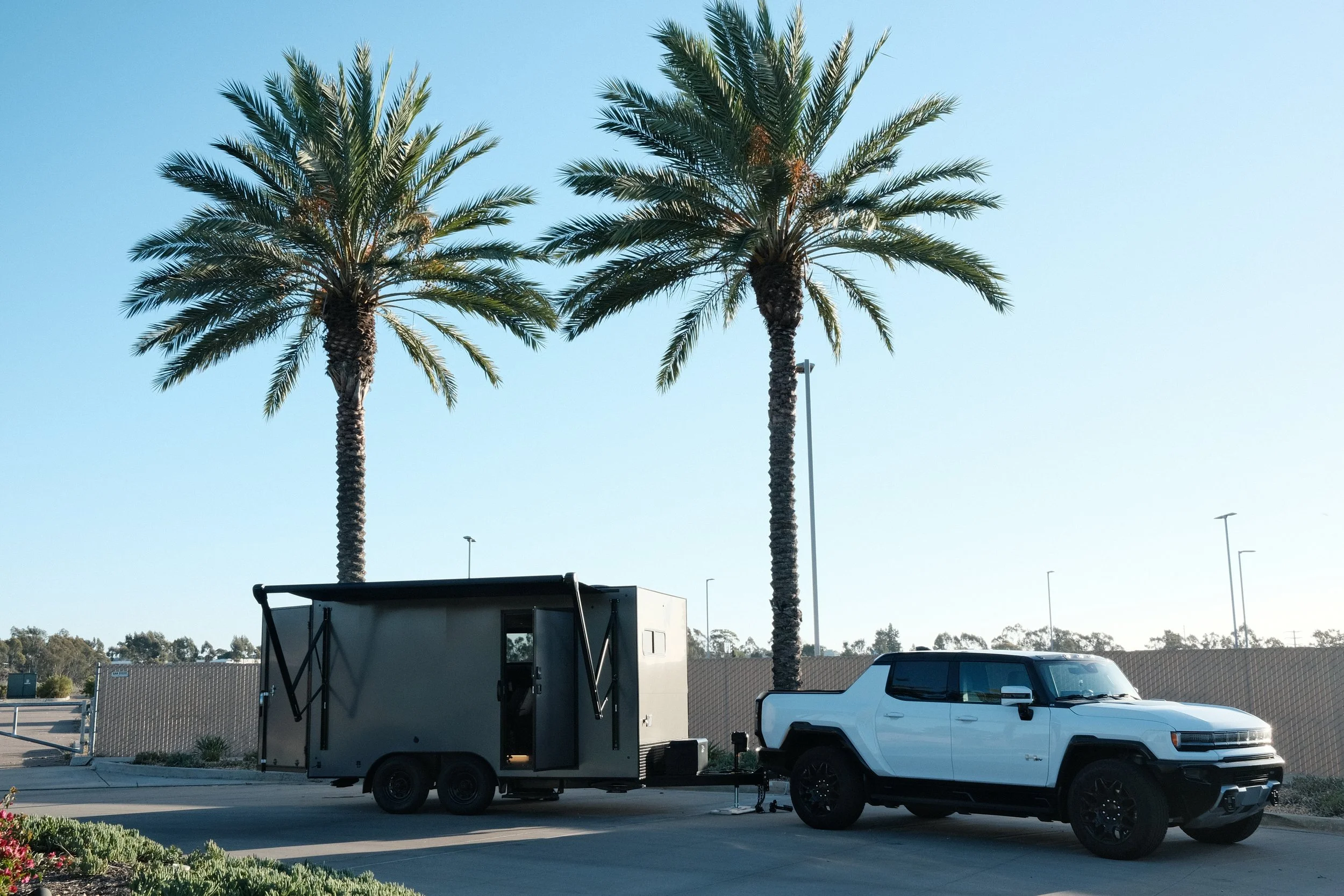 Tilghman trailer and tow vehicle beneath San Diego palm trees