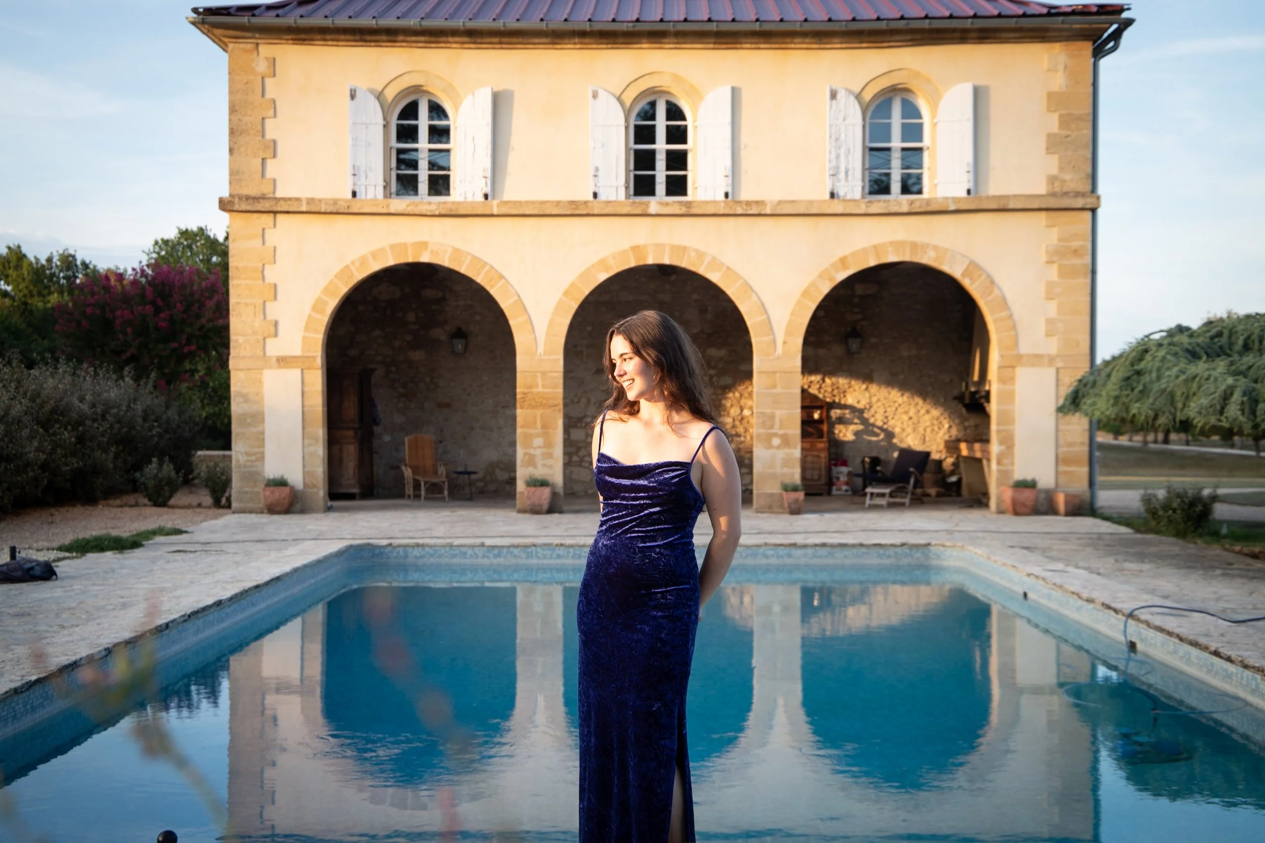 Elizabeth Zmuda beside the pool and pale stone façade at Château de Monboucher