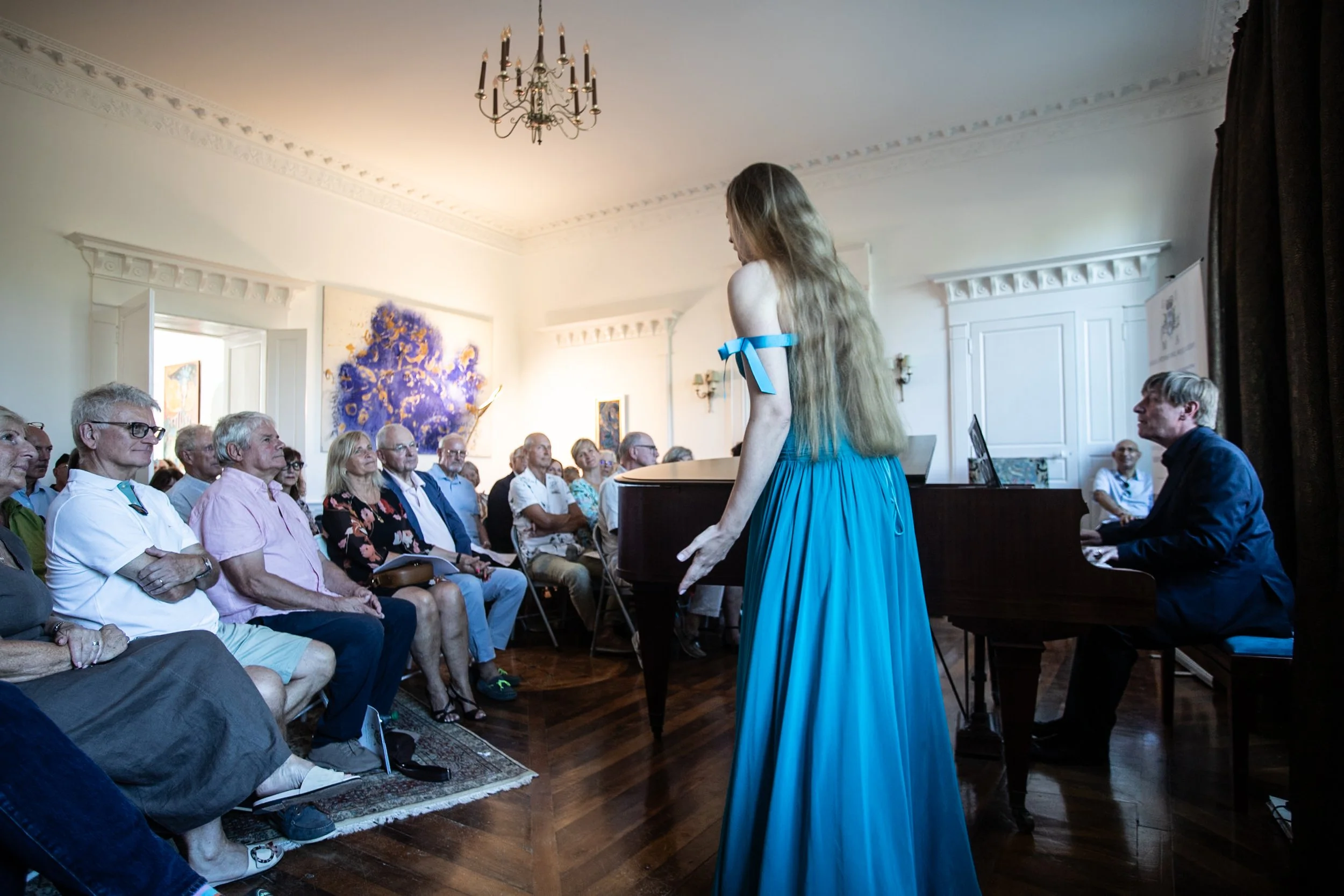 A singer in a turquoise gown entering through the audience during the concert at Château de Monboucher
