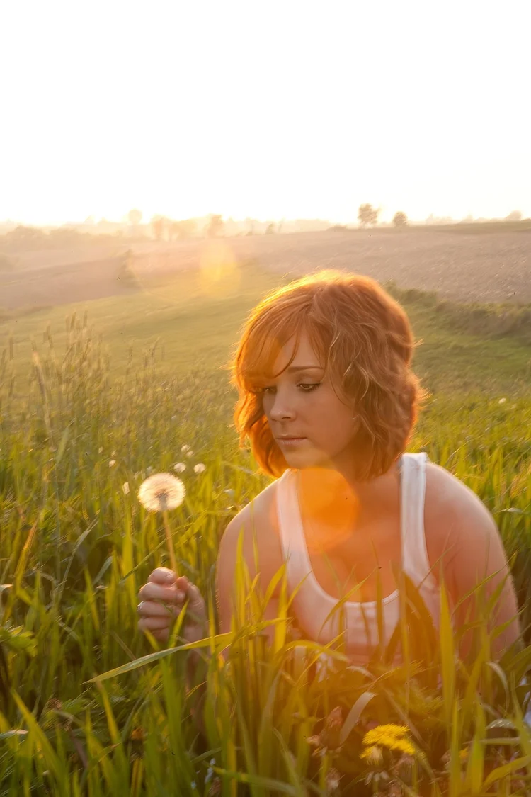 Young woman with a dandelion at sunset