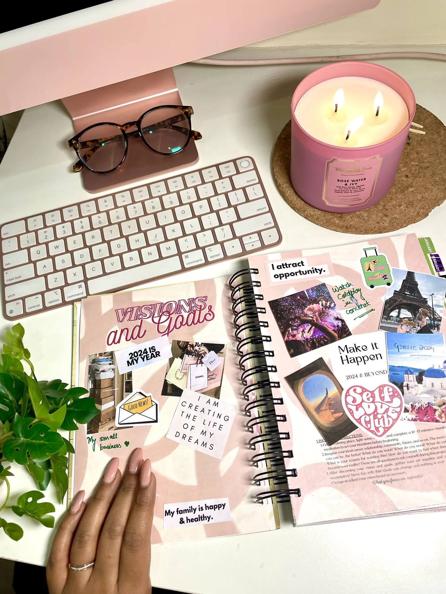 A pink desk with a keyboard, candle and journal