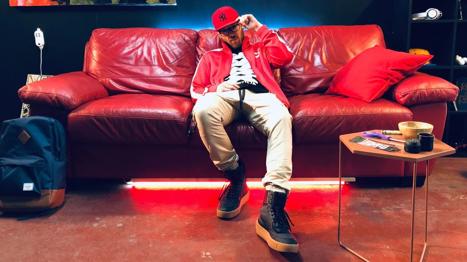 A person in a red cap and red jacket sits on a red sofa.