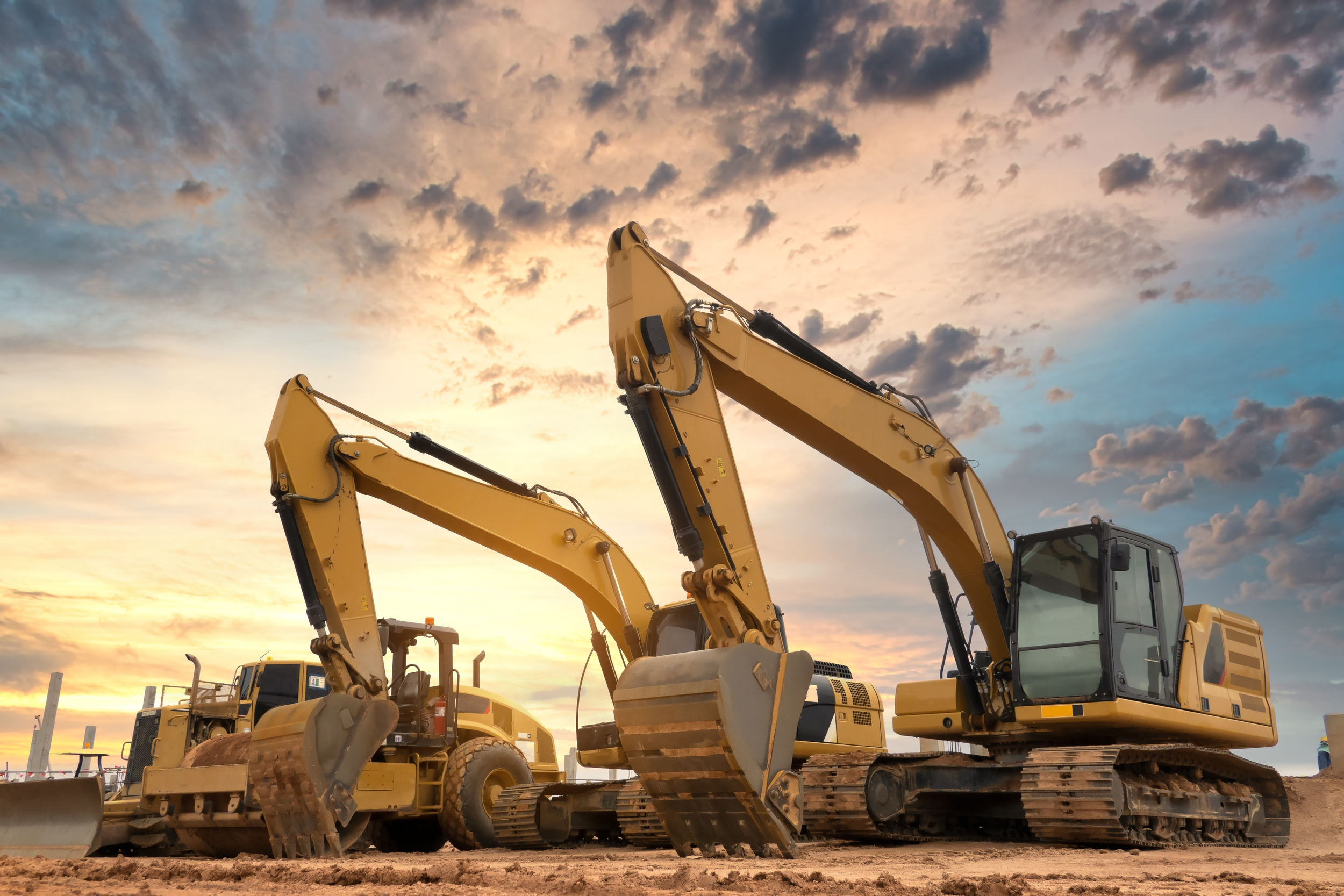 Site operator holding a hard hat in front of a loader