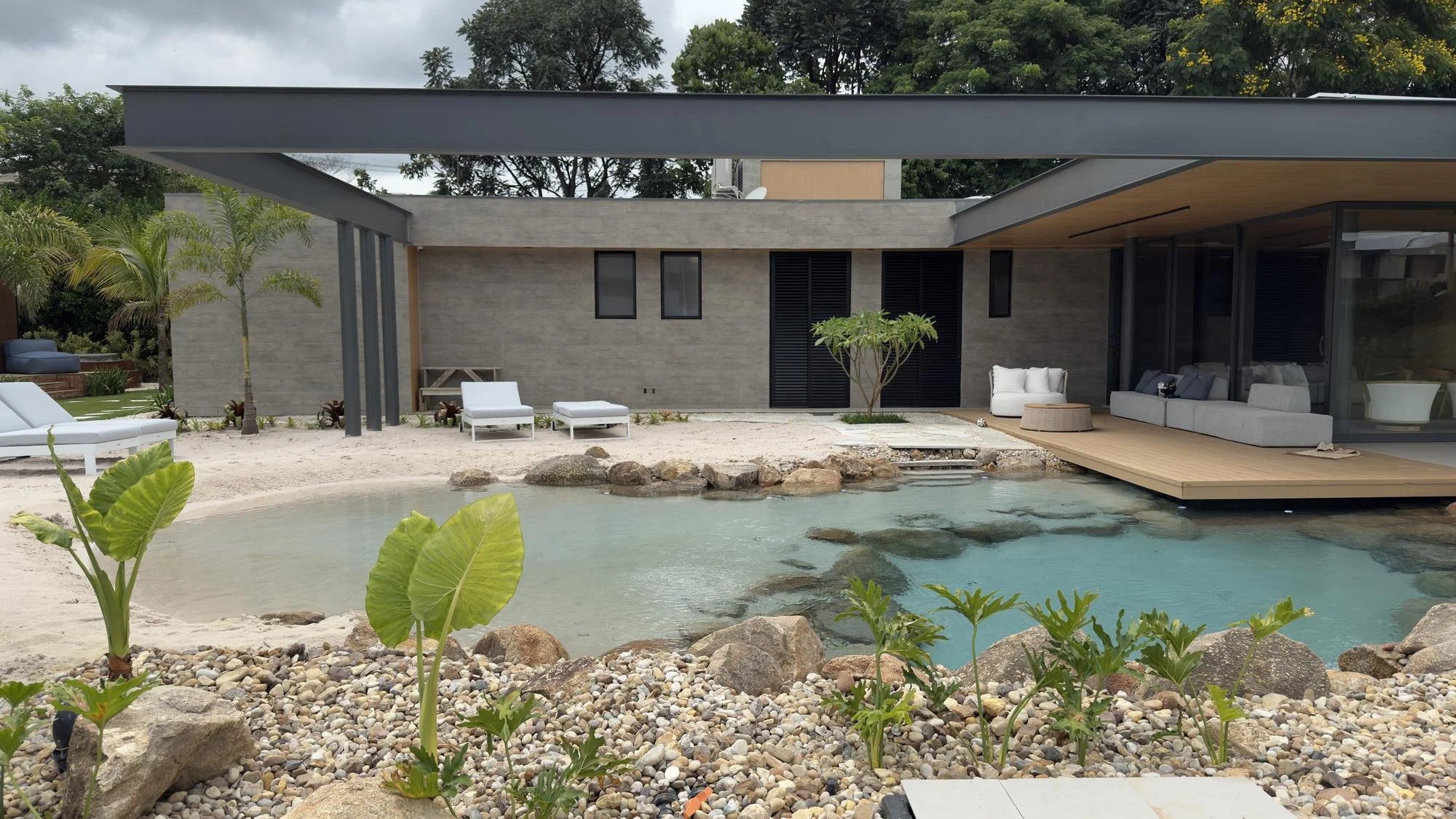 Casa térrea com pátio e piscina natural, paredes revestidas com placas Wall Skin em tom de pedra cinza