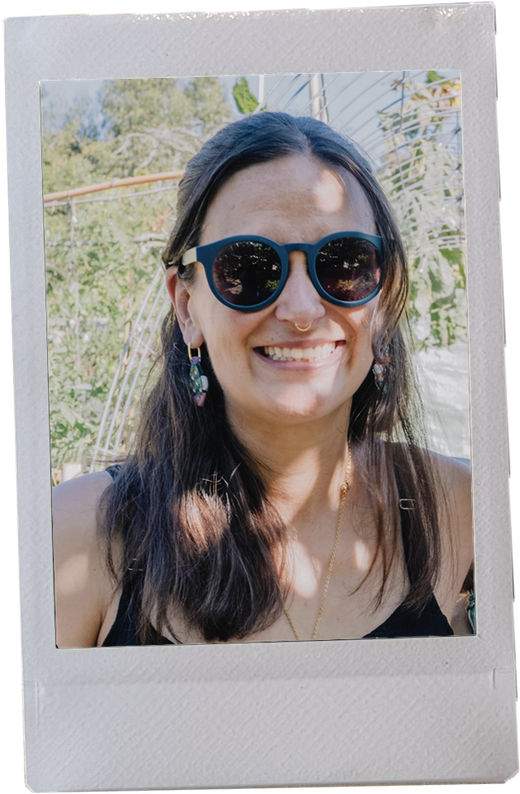 Nara Bopp smiling in round blue sunglasses in a garden