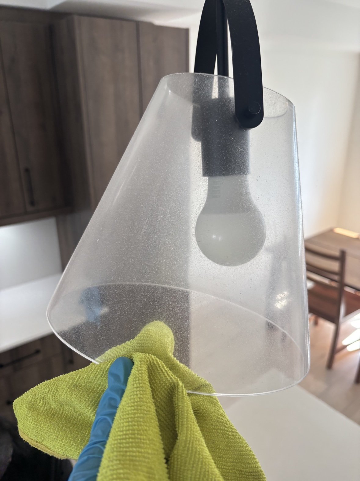 Glass pendant light shade coated in dust being wiped, before cleaning
