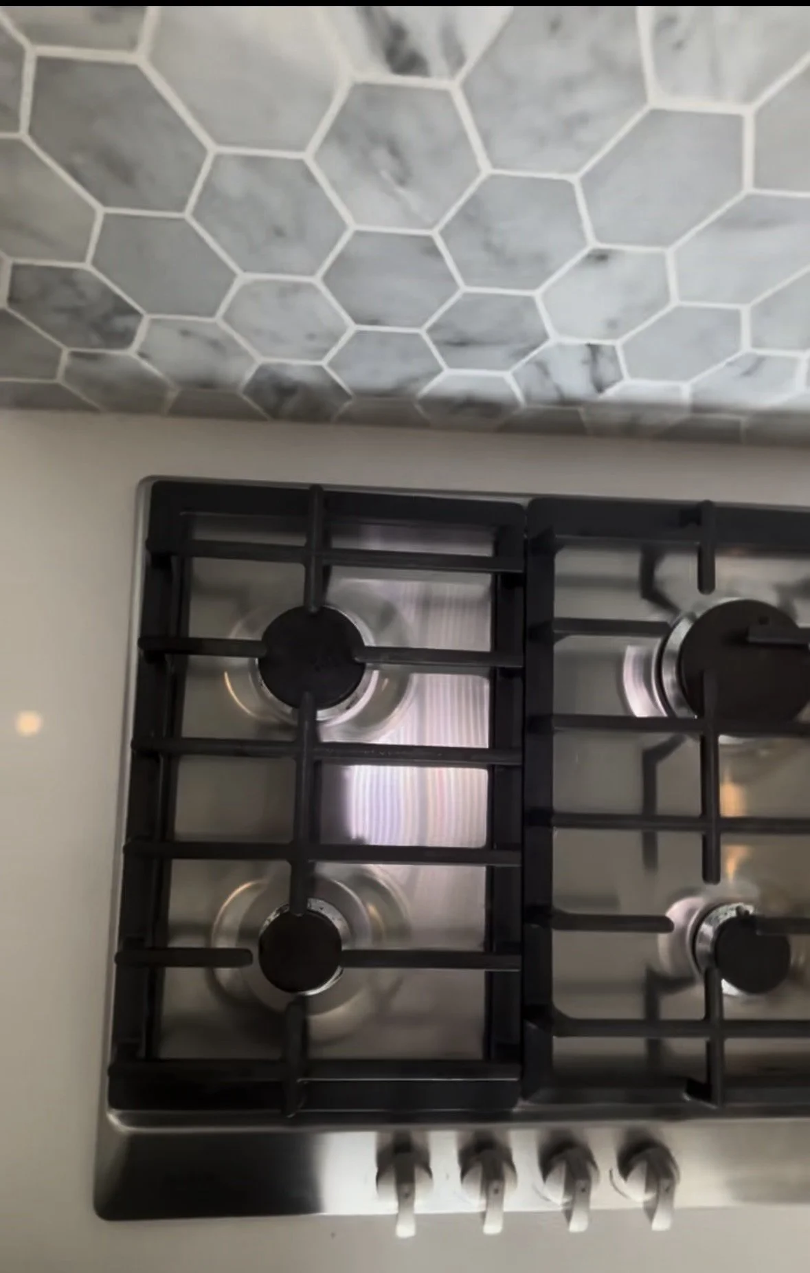 Gas stovetop with grates replaced, stainless steel polished to a shine, after cleaning