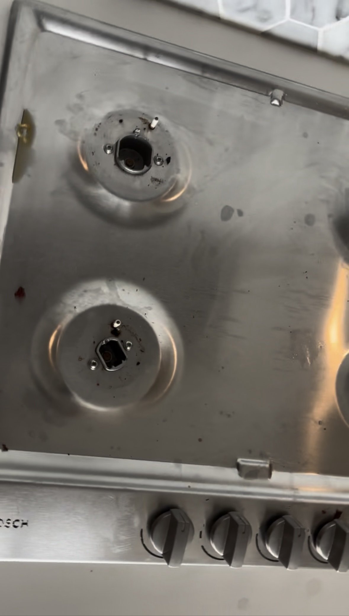 Gas stovetop with grates removed, burners caked in grease and grime, before cleaning