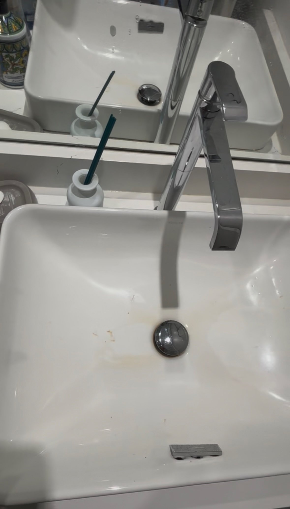 White bathroom sink with stains and grime around the drain, before cleaning
