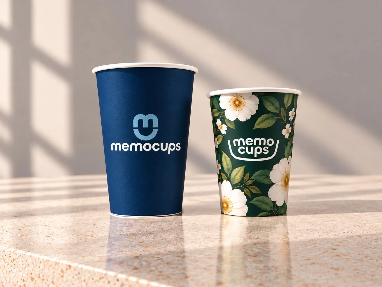 Two premium custom printed paper cups: a navy blue MemoCups logo cup and a green floral wraparound design