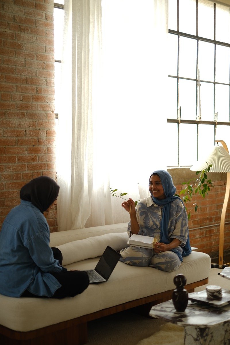Jeem's founders working together on a couch with a laptop and notebook