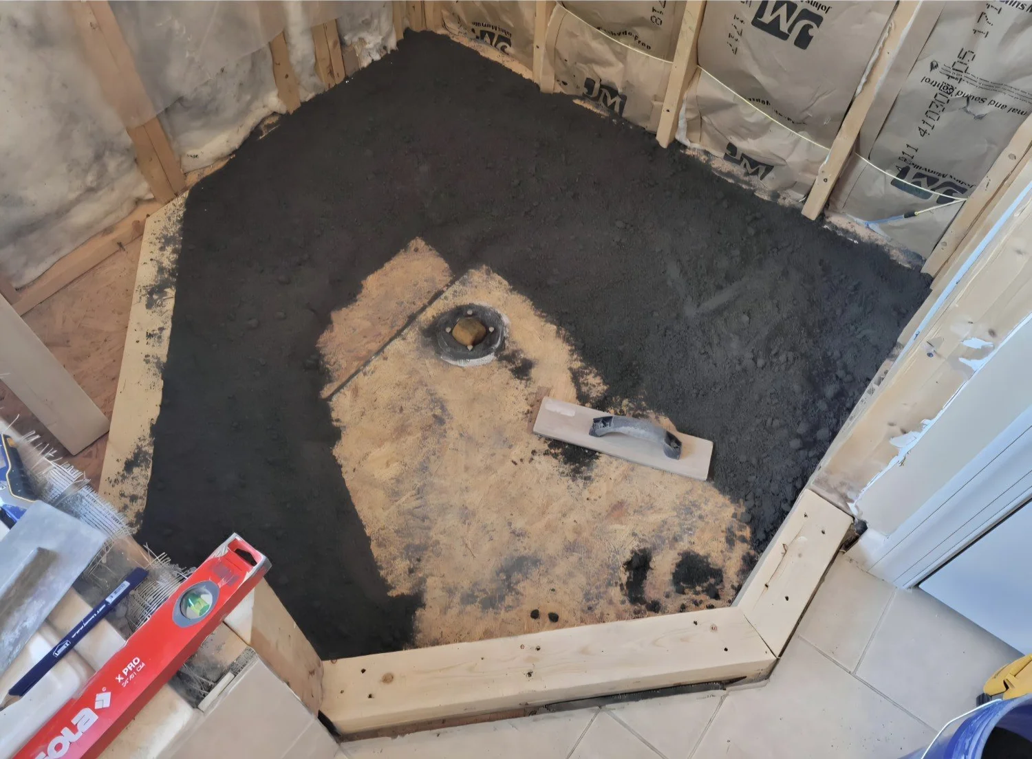 Wood shower base with drain and mortar being placed around the edges
