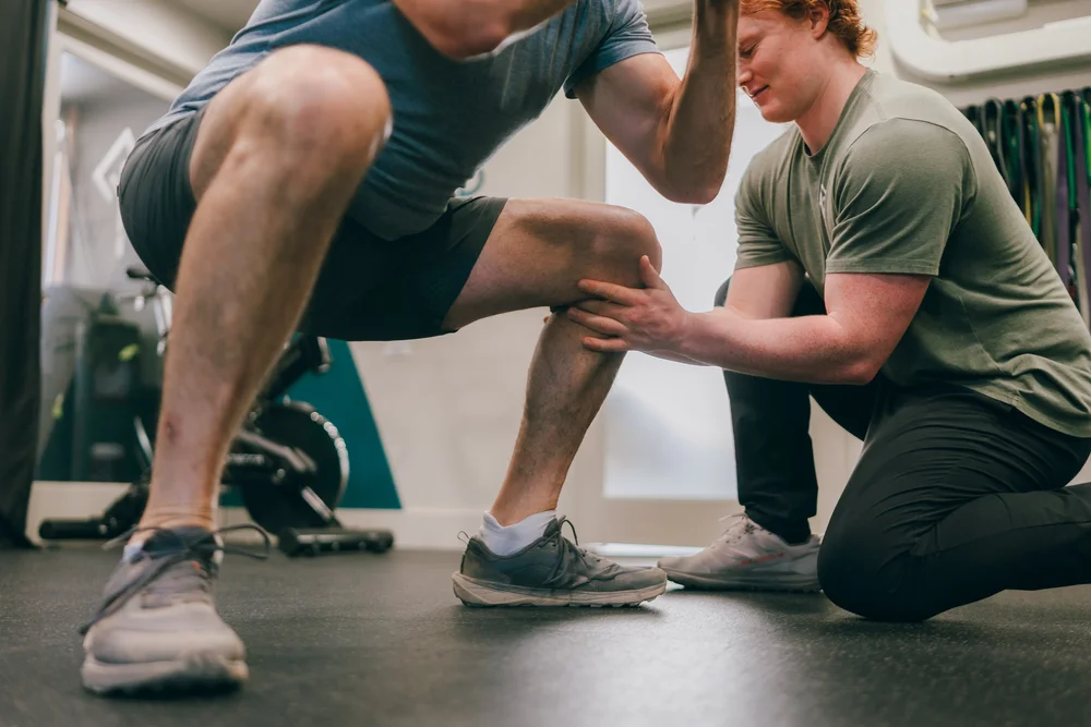 A physical therapist assessing a patient's knee during a lunge