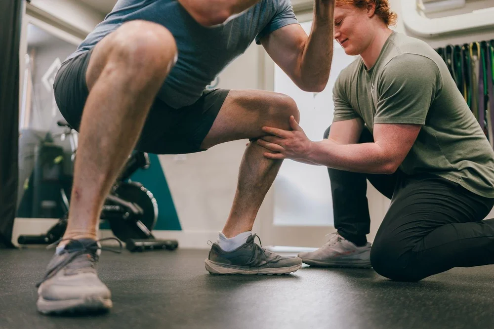 A clinician coaching a patient through a loaded squat