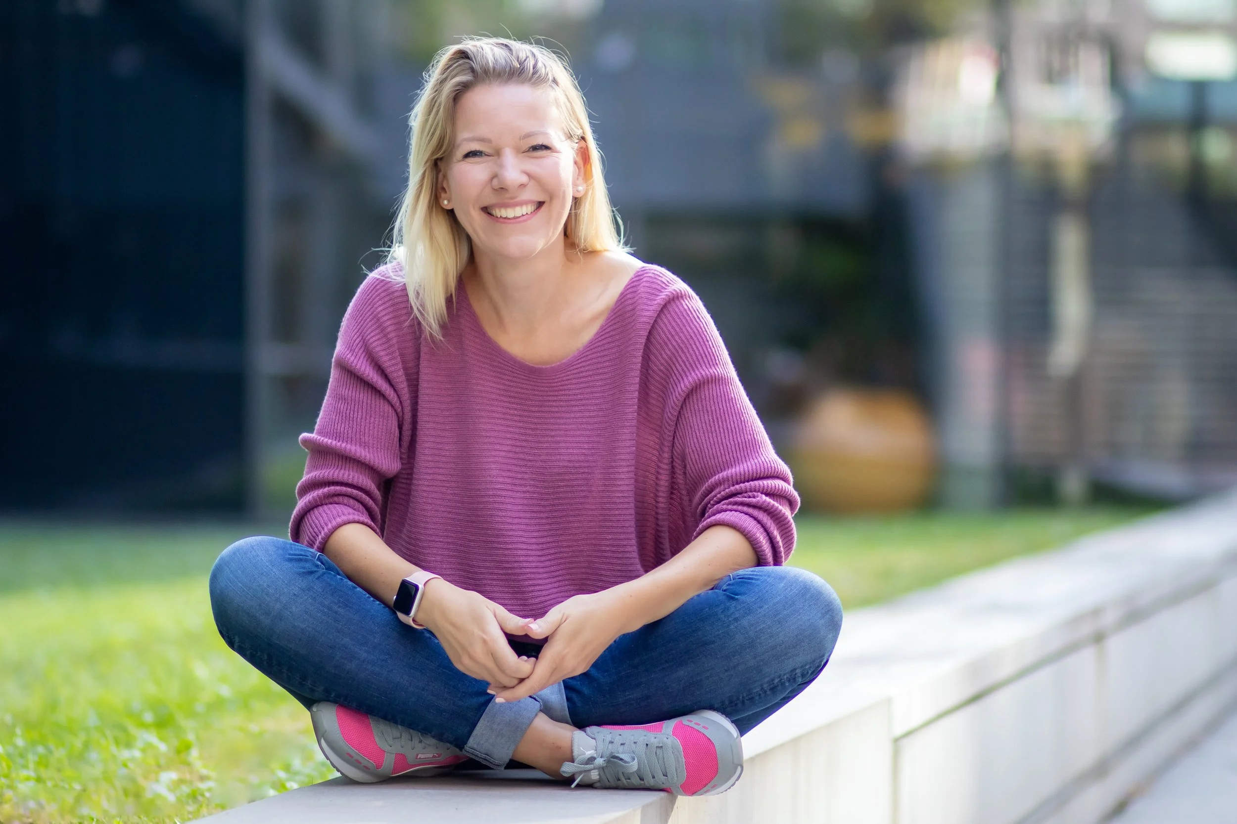 Denise Spekowius, Sales Coach, sitzend auf einer Mauer im Freien