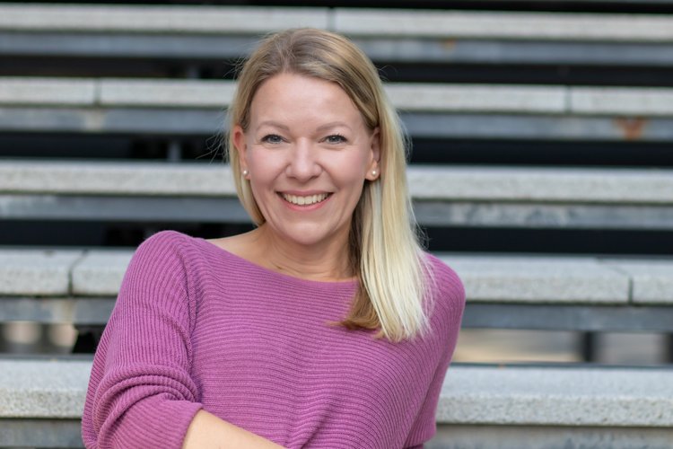 Denise Spekowius, Sales Coach und Trainer-Mentorin, an einer Treppe lehnend