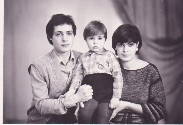 A black-and-white portrait of two adults with a young child between them.