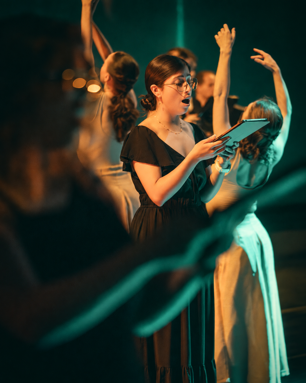 A Verdigris singer holds her score as other performers raise their arms around her.