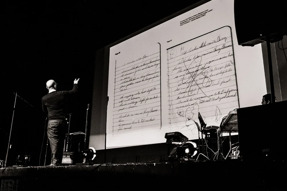 A presenter gestures toward projected pages of Betty Klenck’s handwritten notebook.