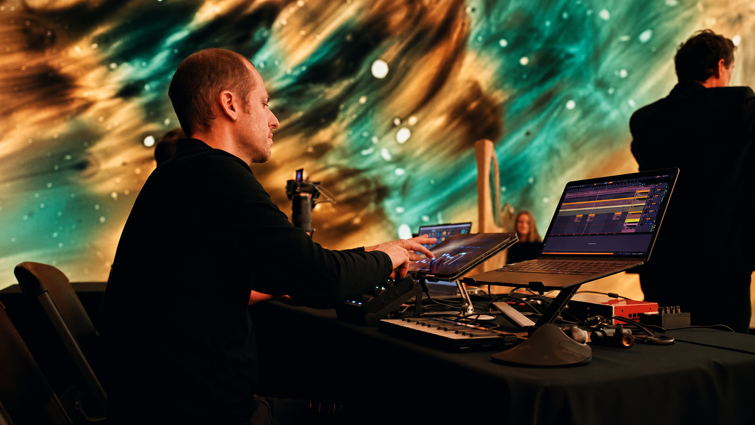 Ricardo Romaneiro performing on an electronic controller before a liquid-light projection.