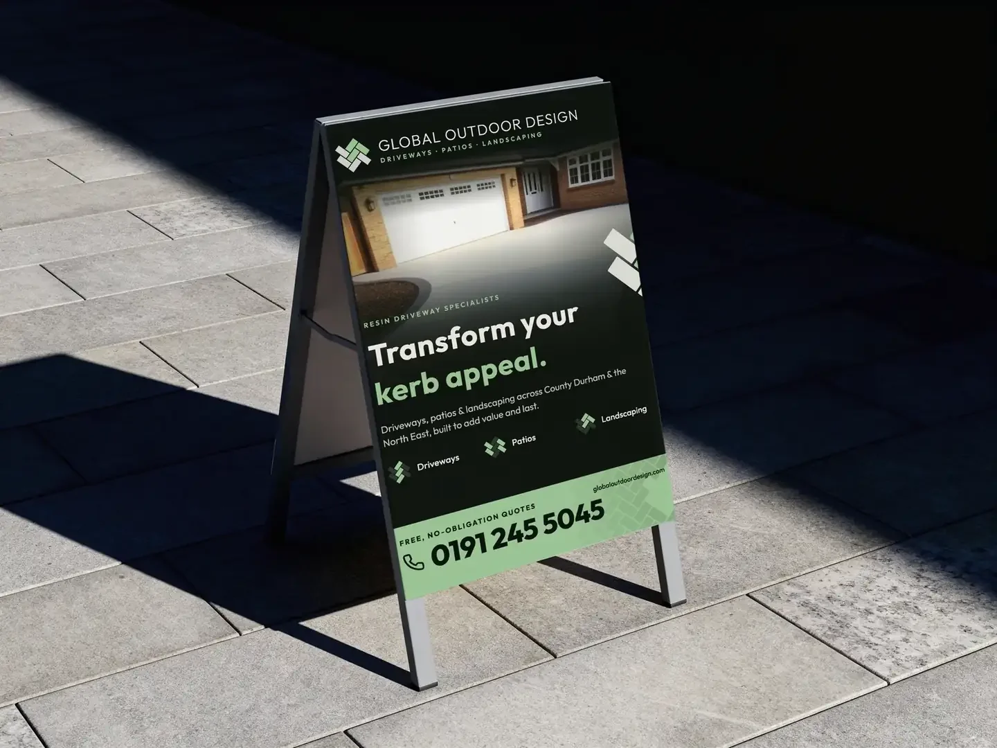 Global Outdoor Design A-board sign on a paved forecourt in low sun: a driveway photo, the line Transform your kerb appeal, and a green panel with the phone number