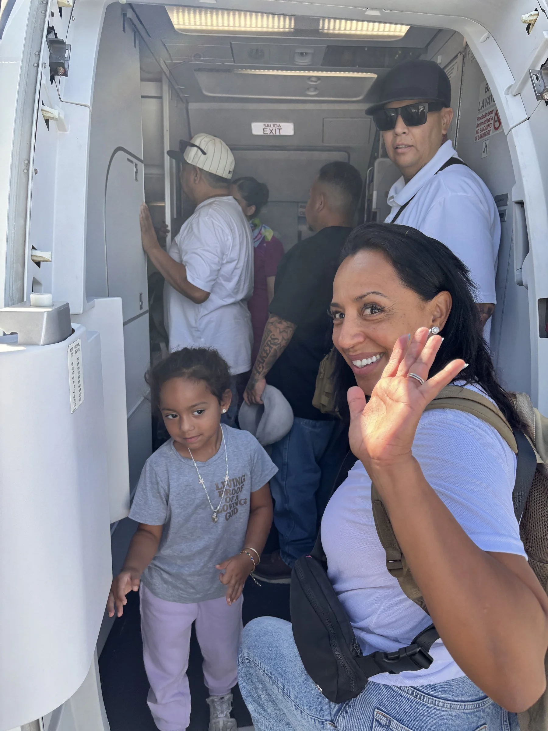 Volunteer waving from vehicle doorway during field travel