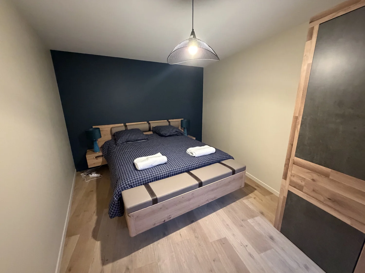 Chambre rénovée avec lit en bois et mur bleu – DõmHõ