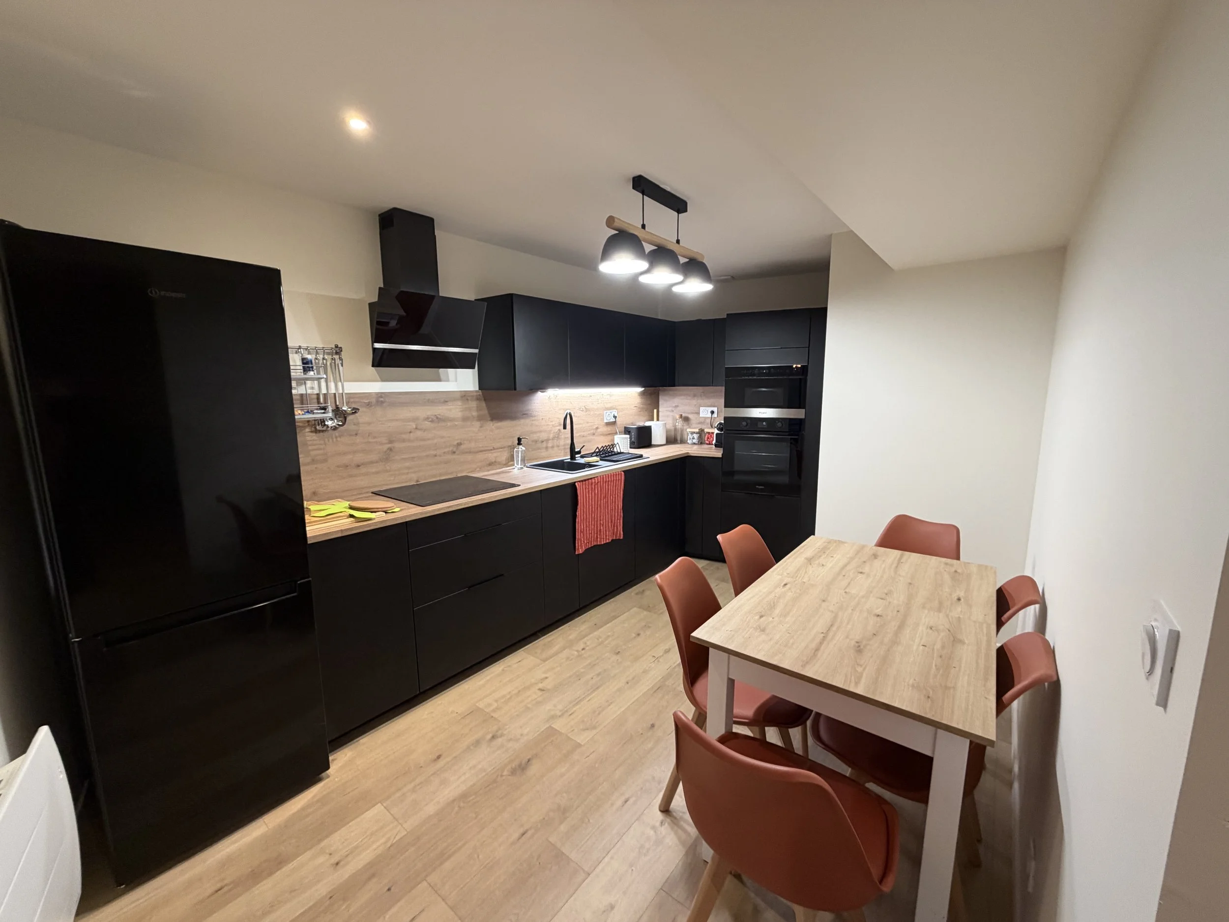 Cuisine rénovée noire et bois avec table et chaises terracotta – DõmHõ