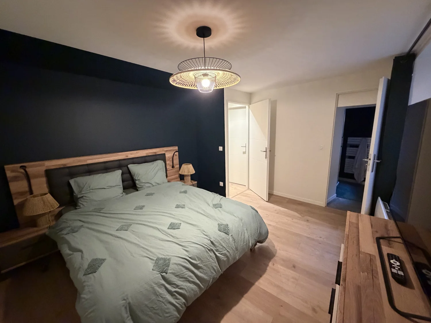 Chambre rénovée mur bleu nuit, suspension en rotin et parquet – DõmHõ